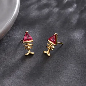 Elegant 24k gold-plated fishbone stud earrings with pink zircon on stone background