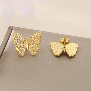 Detailed close-up of golden butterfly earrings with delicate white pearl inlay details