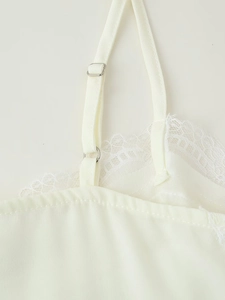 Detail of adjustable silver buckle and lace stitching on beige satin camisole top