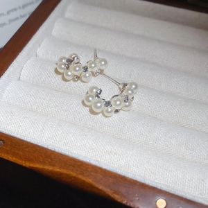 Close-up of elegant C-shaped pearl earrings with rhinestones in a luxury jewelry box