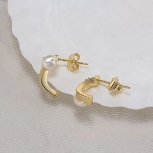 Detail of gold S925 silver earrings with freshwater pearls on a white seashell