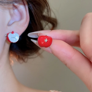 Detailed close-up of a red apple earring with a gold star accent and glossy finish