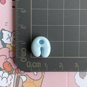Mini light blue U-shaped resin letter bead measured on a cm ruler for craft DIY