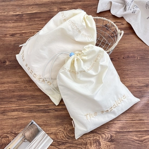Detail of beige canvas drawstring storage bags with premium embroidery and blue cord locks