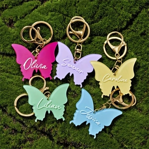 Close-up of colorful resin butterfly keychains with custom names on green moss