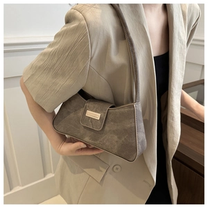 Detail of taupe faux suede underarm bag with metal buckle shown on a shoulder