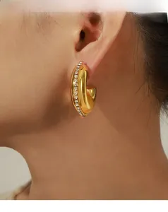 Nahaufnahme von Vintage C-Goldohrringen mit Zirkonia-Inlay, am Ohr getragen