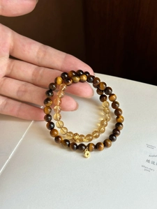 Close-up of double-layer tiger eye and citrine beaded bracelet with gold coin pendant