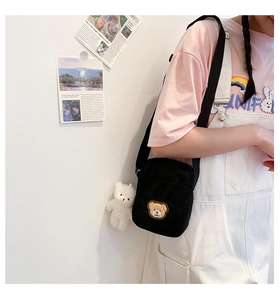 Detail of black corduroy crossbody bag with cute bear embroidery and plush charm