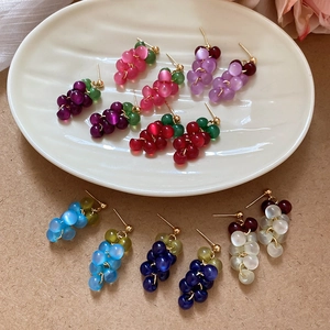 Detailed view of colorful resin grape cluster earrings with cat-eye beads and gold posts