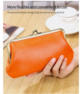 Detail of an orange vintage leather clutch purse held over a warm cafe table background