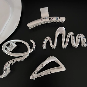 Macro detail of silver matte hair claws with colorful zircons and star heart enamel charms