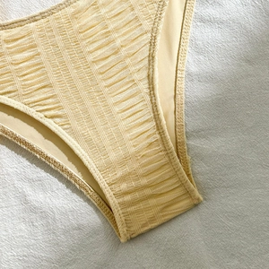 Detail of light yellow mesh bikini bottoms showing pleated lace texture and fine stitching