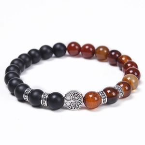 Close-up of Tree of Life charm on tiger eye and matte volcanic stone beaded bracelet