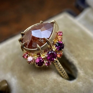 Retro gold ring featuring a pear-cut orange gemstone and pink stones in a vintage style