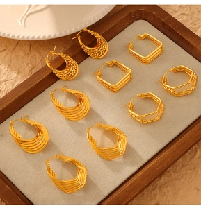 Flat lay of multiple geometric gold earrings including tiered squares and textured hoops