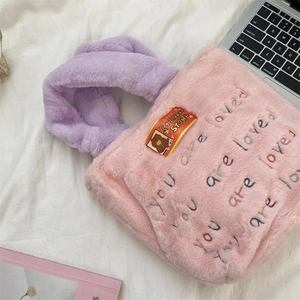Gros plan sur le sac fourre-tout en peluche rose avec broderie 'you are loved'