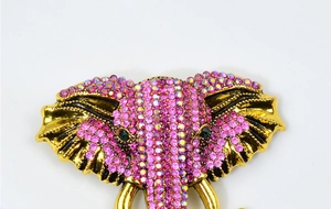 Détail d'une broche éléphant dorée sertie de strass roses et d'un œil en cristal vert