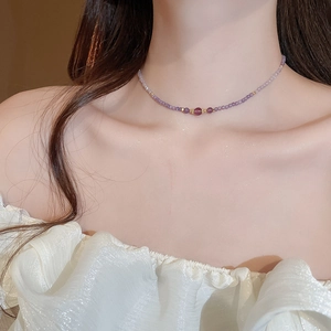 Detailed close-up of zircon and purple amethyst beaded necklace worn on a woman's neck