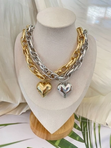 Detailed view of chunky gold and silver chain necklaces with polished heart pendants