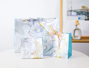 Detailed view of three marble pattern gift bags with elegant silk ribbon handles
