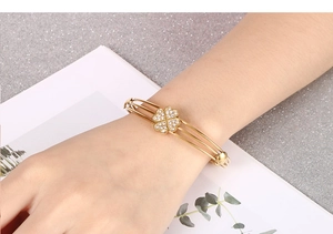 Dettaglio del bracciale a quadrifoglio dorato con zirconi indossato da una modella
