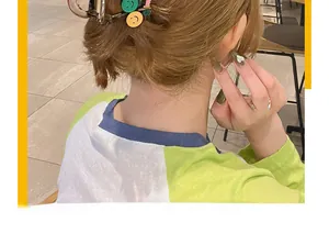 Detailed view of hair claw clip with colorful smiley faces used in a stylish updo hairstyle