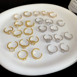 Collection of gold and silver open rings with sparkling zircon stones on a white plate