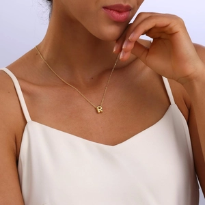 Detailed view of polished 18K gold plated bubble letter R pendant necklace on model