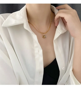 Close-up of a double-layered gold and silver necklace with an interlocking triple ring pendant