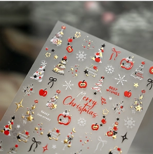 Vue macro d'autocollants 3D pour ongles de Noël avec pomme rouge et sapin doré gaufré