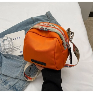 Detail of the orange oxford crossbody bag with embroidered wide strap on denim fabric