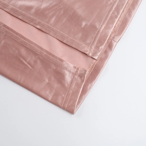 Detail shot of dusty pink satin dress showing thigh-high slit and smooth fabric texture