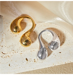 Macro detail of sculptural double teardrop open rings in polished gold and silver finish