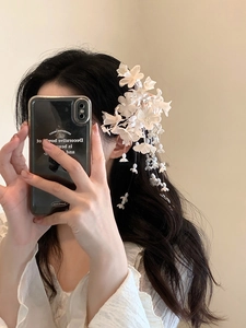 Close-up of white lily of the valley hair clip with elegant tassels on person