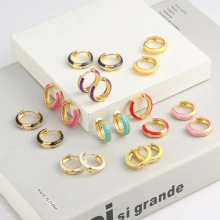 Close-up of colorful enamel hoop earrings set with gold plating on white display