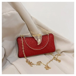 Close-up of red sequined clutch bag with gold leaf clasp and metal chain strap