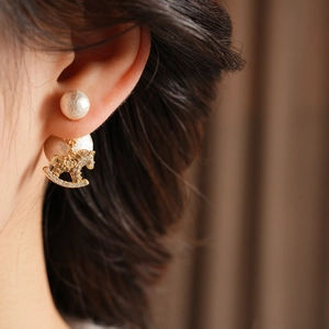 Detail of earring with white pearls and gold rocking horse pendant inlaid with zircons