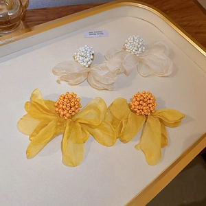 Detail of floral earrings featuring white and yellow fabric petals and beaded centers