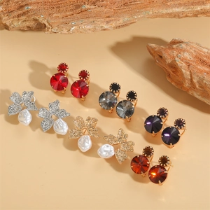 Set of acrylic flower earrings and colorful crystal studs on natural stone backgrounds