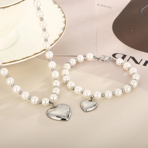 Ensemble collier et bracelet en perles avec pendentif cœur argenté sur un bureau