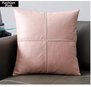 Close-up of pink faux leather pillow cover with cross-stitch design on green sofa