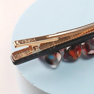 Macro shot of the Forea engraved golden metal hair clip with iridescent shell shards