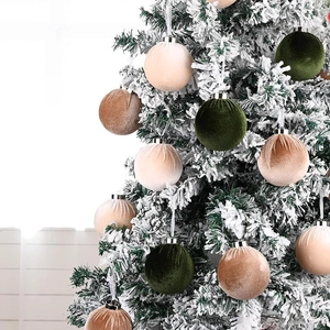 Détail de boules de Noël en velours aux tons terreux suspendues sur un sapin enneigé