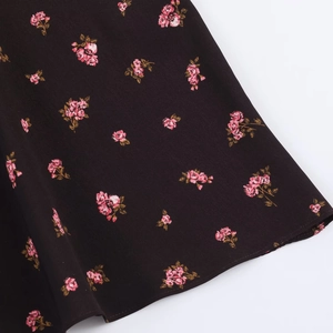 Gros plan détaillé sur l'imprimé floral rose et les coutures de la robe midi noire