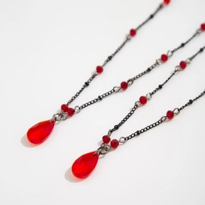 Macro detail of gothic choker with red faceted teardrop charms and black chains