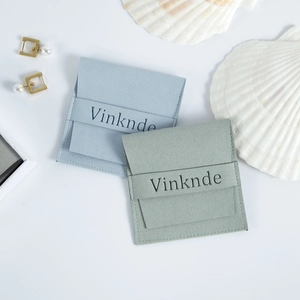 Vue macro de pochettes à bijoux en microfibre suédée bleu clair et vert avec boutons