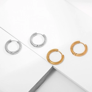 Detailed close-up of gold and silver geometric hoop earrings on minimalist display blocks