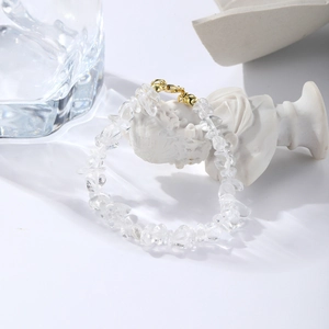 Detail of bohemian white crystal stretch bracelet with gold lobster clasp on white background