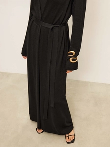 Close-up of black knitted cardigan sleeve with elegant gold snake metal detail and tie belt